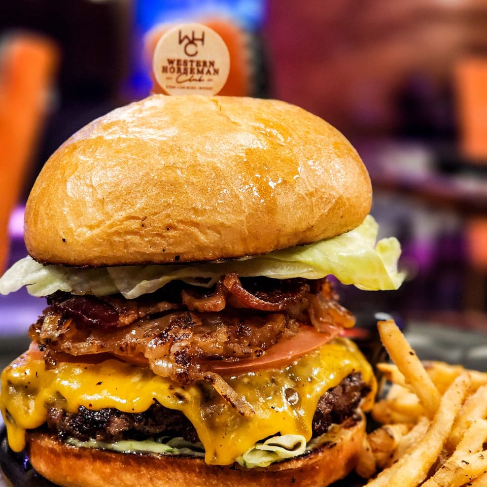 Bacon cheeseburger with lettuce, tomato, melted cheese, and fries.